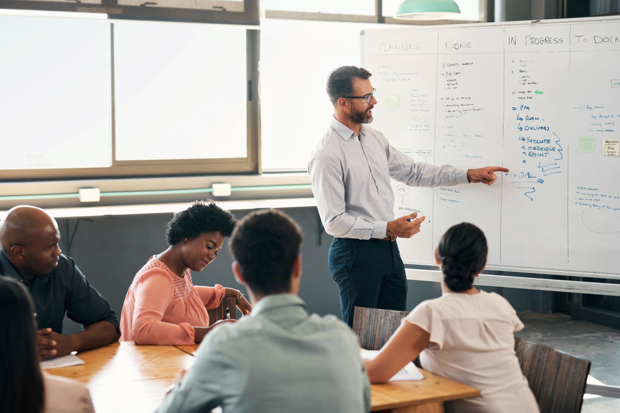 Presentation, speaker or leadership with man leader for coaching, training or business meeting in workshop. Corporate, teamwork or collaboration for planning financial marketing budget strategy