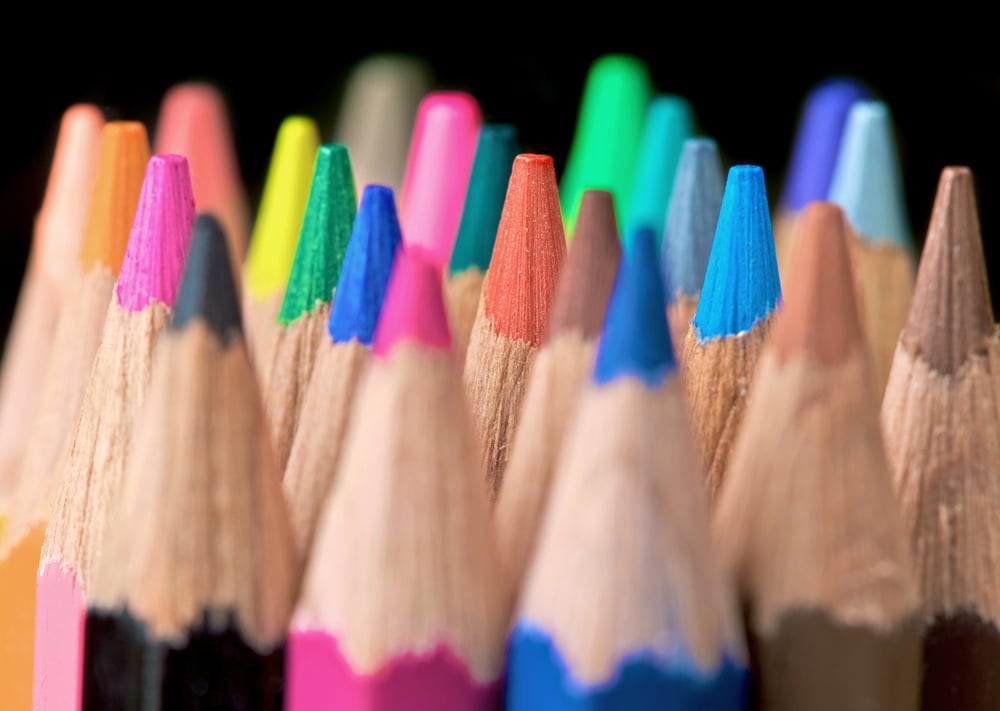 assorted colour pencils close up in perspective with focus on the tips using a shallow depth of field - isolated over a black background